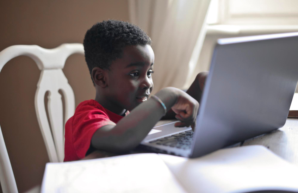 Girl writing on a pad in front of a monitor